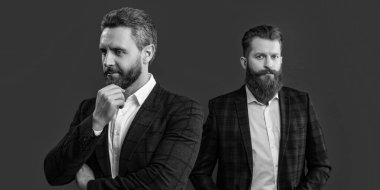 Seçici odaklı erkek giyimli sakallı adamlar. Erkek giyim kuşamı giyen zarif erkekler. Erkek giyim ceketi giymiş iki adamın stüdyo fotoğrafı. Erkekler giyim kuşamında, bordo arka planda izole edilmiş..