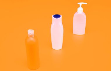 Vücut yıkama ürünleri için kapaklı ve pompalı çok renkli kozmetik paketleme sarı arka plan fotokopi alanı, şişeler.