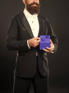 Smokinli gülümseyen adam siyah arka planda siyah papyonlu, kutulu. Sevgililer Günü.