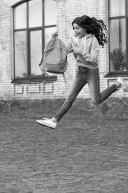 amazed school girl jump childhood at the street. photo of school girl jump childhood with backpack. school girl childhood jump outdoor. school girl jump childhood outside.