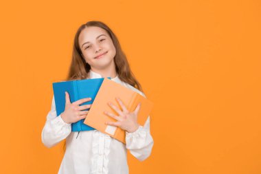 Neşeli çocuk, sarı arkaplanlı, fotokopi ve eğitim alan okul kitabını tutuyor..