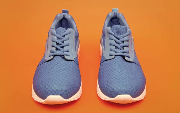 pair of comfortable sport shoes. sporty blue sneakers. shoes on orange background. shoe store. shopping concept. footwear for training. athletic footgear for running.