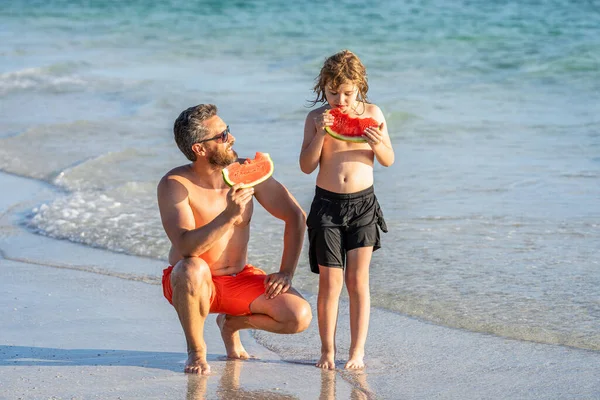 Father dad and son eating watermelon. father and son on summer vacation. single dad father with child son in childhood. Loving father and son enjoying happy time together at sea.