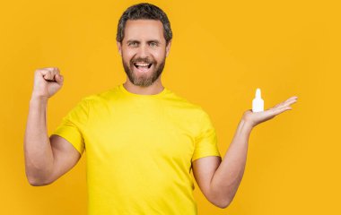 Stüdyoda burun tıbbı yapan mutlu bir adam. Burun tıbbı damlaları olan bir adamın fotoğrafı. Burun tıbbı olan adam sarıda izole edilmiş. Geçmişinde burun tıbbı olan bir adam..