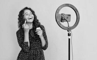 Uzun kıvırcık saçlı gülen kız blog tutuş pudra fırçası videosu çekiyor.