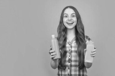 şaşırmış çocuk sarı arka planda şampuan şişesi ile.