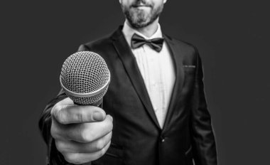 Sunucu mikrofonu kırmızı arkaplanda izole etti. Stüdyoda mikrofon. Mikrofonlu el. el tutuş mikrofonunun fotoğrafı.