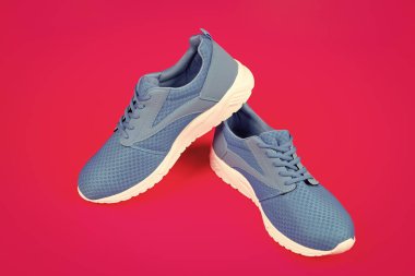 Pembe arka planda bir çift rahat mavi spor ayakkabı, yeni bir çift..