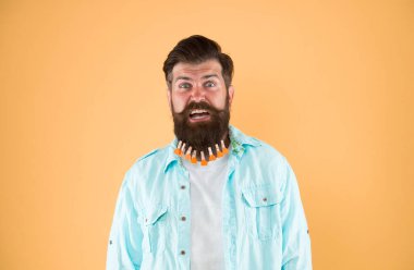 Adam sakallı mandal. Kalpleri mandallı vahşi bir hippi. Sakallı adam sıradan sarı arka plan. Sevgililer Günü. Kuaförde saç kurutma. erkek için bireysel saç şekli.