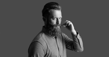 Traşsız adamın stüdyo fotoğrafı. Bıyık ve sakal bakımı. Yakışıklı, sakallı ve bıyıklı. Gri arka planda sakallı ve bıyıklı traşsız bir adam..