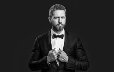 Resmi papyon takan smokinli adam. Resmi takım elbiseli smokinli adamın fotoğrafı. Resmi smokin giyen adam kırmızı arka planda izole edilmiş. Resmi giyinme stüdyosundaki smokin giyen adam..