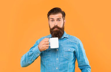 Elinde çay fincanı olan sürpriz bir adam sarı arka plan, sürpriz..