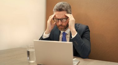 Aşırı çalışan iş adamlarının baş ağrısı olur. Aşırı çalışan iş adamının fotoğrafı baş ağrısı yapar. Çok çalışan iş adamının ofiste başı ağrıyor. Çok çalışan iş adamının çalışırken başı ağrıyor..