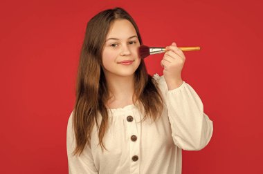 pozitif çocuk makyaj fırçasıyla yüzüne pudra sür.