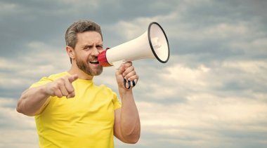 Sarı gömlekli adam arka planda megafonla bağırıyor. reklamcılık.