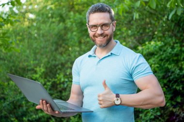 Programcı başparmağını kaldırdı. Programcı açık havada. Bilgisayarda çalışan programcı. Bilgisayarda programcının fotoğrafı..