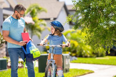 Baba oğul bisiklet gezintisinin keyfini çıkarıyorlar. Baba ve oğul bisiklet macerasında. Baba ve oğul ikilisi resimli manzarada pedal çeviriyor. Aile bisikleti gezisi. Destekleyici baba oğluna ilk bisiklet sürüşünde rehberlik ediyor..