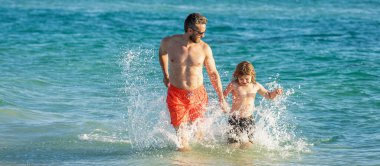 Baba oğul, yaz tatilinin tadını çıkarıyor. Denizde baba ile oğul arasında özel anlar. Baba oğul bağ kurma ilişkisi. Baba oğul deniz sahilinde koşuyor. Mutlu aile.