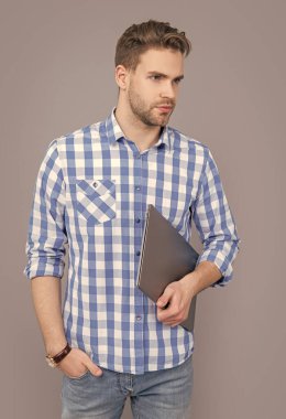 Laptop stüdyosu olan üniversite öğrencisi. Dizüstü bilgisayarı tutan ciddi bir adam. Laptop kullanıcısı gri renkte izole edildi. Lise eğitimi.