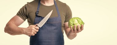 Önlüklü bir adam beyaz arka planda izole edilmiş lahana ve bıçak tutuyor..