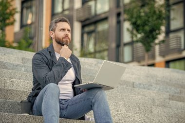 Bilgisayarlı serbest çalışan bir adam olduğunu düşünüyor. Bilgisayarlı serbest insan iletişimi. Serbest çalışma kavramı. Serbest çalışan adam dışarıda dizüstü bilgisayarda çalışıyor..