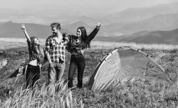 Feel freedom. Happiness concept. Hiking activity. Friends set up tent on top mountain. Camping gear. Camping equipment. Weekend in mountains. Man and girls having fun in nature. Camping tent.