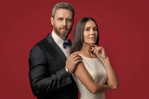 stock image formal tuxedo couple of two isolated on red background. couple in formal tuxedo. studio shot of formal tuxedo couple. elegant couple wear formal tuxedo.