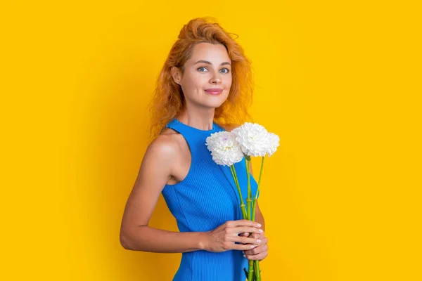 cheerful woman with spring flowers in studio. woman with spring flowers on background. photo of woman with spring flowers. woman with spring flowers isolated on yellow.