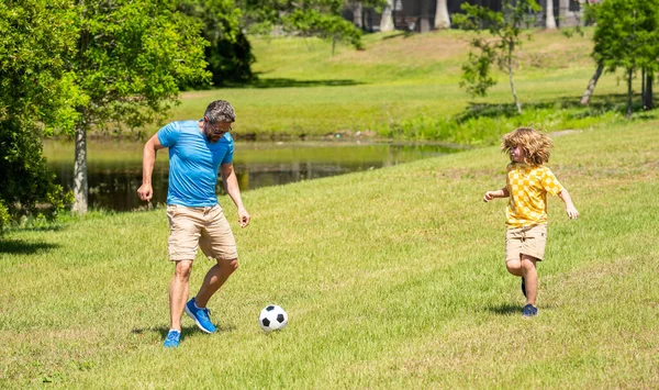 Active father son playing football in summer. Father and child son teaming up outdoor. Father dad and son enjoying outdoor activities together. Outdoor adventures between father and son. having fun.