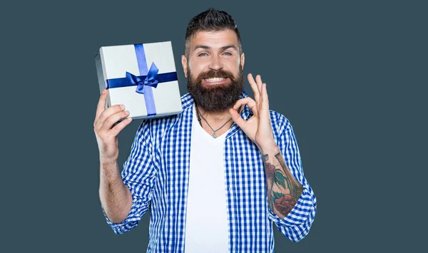 stock image mature bearded guy with wrapped box on grey background.