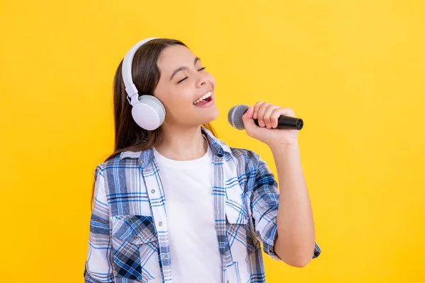 黄色で隔離された音楽マイクに歌うポジティブな女の子 バックグラウンドで歌う十代の歌手少女 ミュージックスタジオでマイクを持った歌手の少女 ヘッドフォンの才能ある音楽歌手少女 — ストック写真
