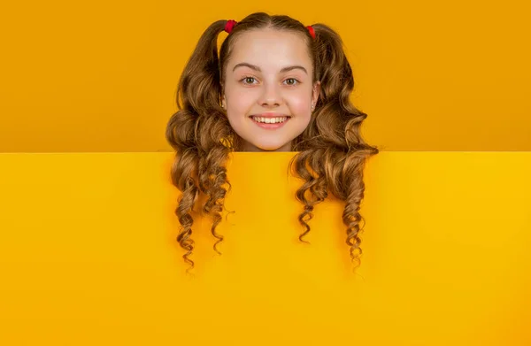 広告のためのコピースペースが付いている空白の黄色いペーパーの後ろの笑顔の子供 — ストック写真