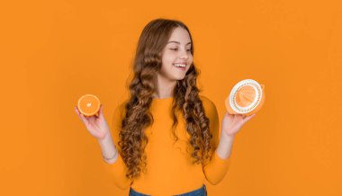 cheerful teen girl hold orange and juicer on yellow background.