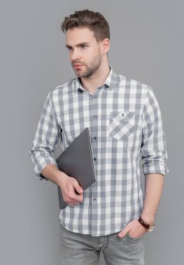 Laptop stüdyosu olan üniversite öğrencisi. Dizüstü bilgisayarı tutan ciddi bir adam. Laptop kullanıcısı gri renkte izole edildi. Lise eğitimi.