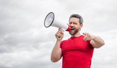 Kırmızı gömlekli adam arka planda hoparlörden bağır. işaret parmağı.