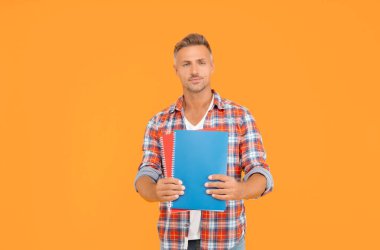 Ciddi bir üniversite öğrencisi eğitim için kitap tutuyor sarı arkaplan, kopya alanı.