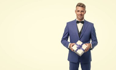 cheerful man in blue suit with gift box isolated on white. valentines day.