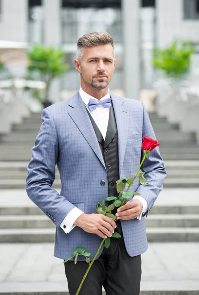 elegant man in tuxedo at romantic occasion. man with romantic present. caucasian romantic man with rose.