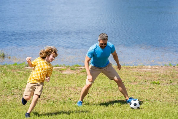 dad have fun with his son. dad and son enjoying childhood adventures outdoor. dad and son playing football during their childhood. Childhood memories of son and his dad. creating lasting memories.