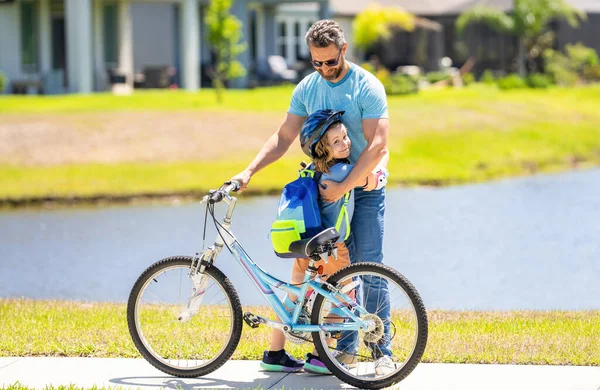 childhood of son supported by fathers care. father embrace son on bicycle at fathers day. active father setting a example for fathers son. fathers parenting with son outdoor. family bonding.
