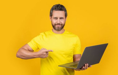 Arka planda erkek programcı, işaret parmağı. Stüdyodaki adam programcı. Dizüstü bilgisayarlı insan programcısının fotoğrafı. Adam programcı sarı üzerine izole.