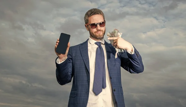 photo of betting man pointing finger on lottery money. betting man with lottery money on sky background. betting man with lottery money outdoor. betting man with lottery money hold phone.