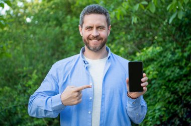 Akıllı telefon sunan adam, işaret parmağı. Adam dışarıda akıllı telefon sunuyor. Adam akıllı telefon ekranına kopyalama alanı sunuyor. Akıllı telefon sunan adamın fotoğrafı.