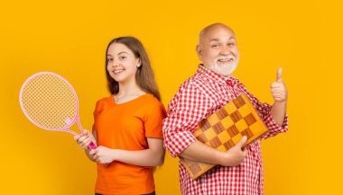 Dedesi badminton raketi ve sarı arka planda satrancı olan neşeli bir kız..