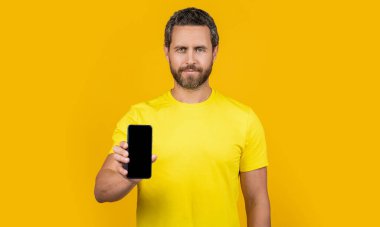Akıllı telefon uygulaması gösteren adam sarıda izole edildi. Adam arka planda akıllı telefon uygulaması gösteriyor. Stüdyoda akıllı telefon uygulaması gösteriyor. Akıllı telefon uygulaması gösteren bir adamın fotoğrafı.