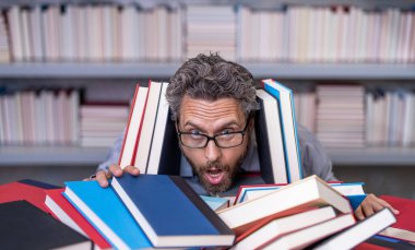 Çok çalışan erkek öğrenci kitapçıda ya da okul kütüphanesinde kitap okuyor. Okulda edebiyat öğretmeni ve kitap. Bilgi günü. Okul sınavına hazırlan. Çok çalışan milenyum öğrencisi kitap okuyor. Dinlenmem gerek..