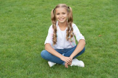 Genç kız çocukluk hayatı tarzında dışarıda oturuyor yaz çimlerinde rahatlıyor..