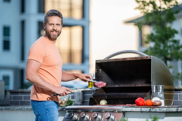man preparing grilled food at backyard barbecue. Smoky grilling aroma. man with hot grill at a barbecue party. man grilling delicious barbecue on a summer day.
