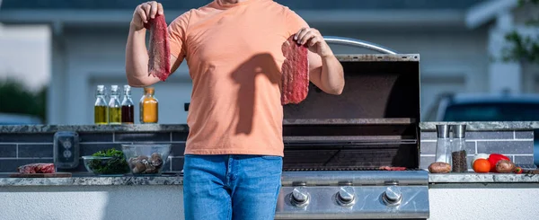 Man cooking on barbecue grill in yard. man cooking at a backyard barbecue. man tending to the grill cooking delicious barbecue under the open sky. Sizzling sensations from the grill.