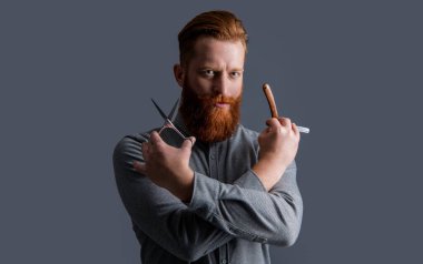 Berber dükkanında elinde makas olan beyaz bir adam. Berber dükkanındaki berber. Berber adam kuaförde makas ve bıçak tutuyor. Berber dükkanı konsepti. Berber adam gri arka planda izole edilmiş..